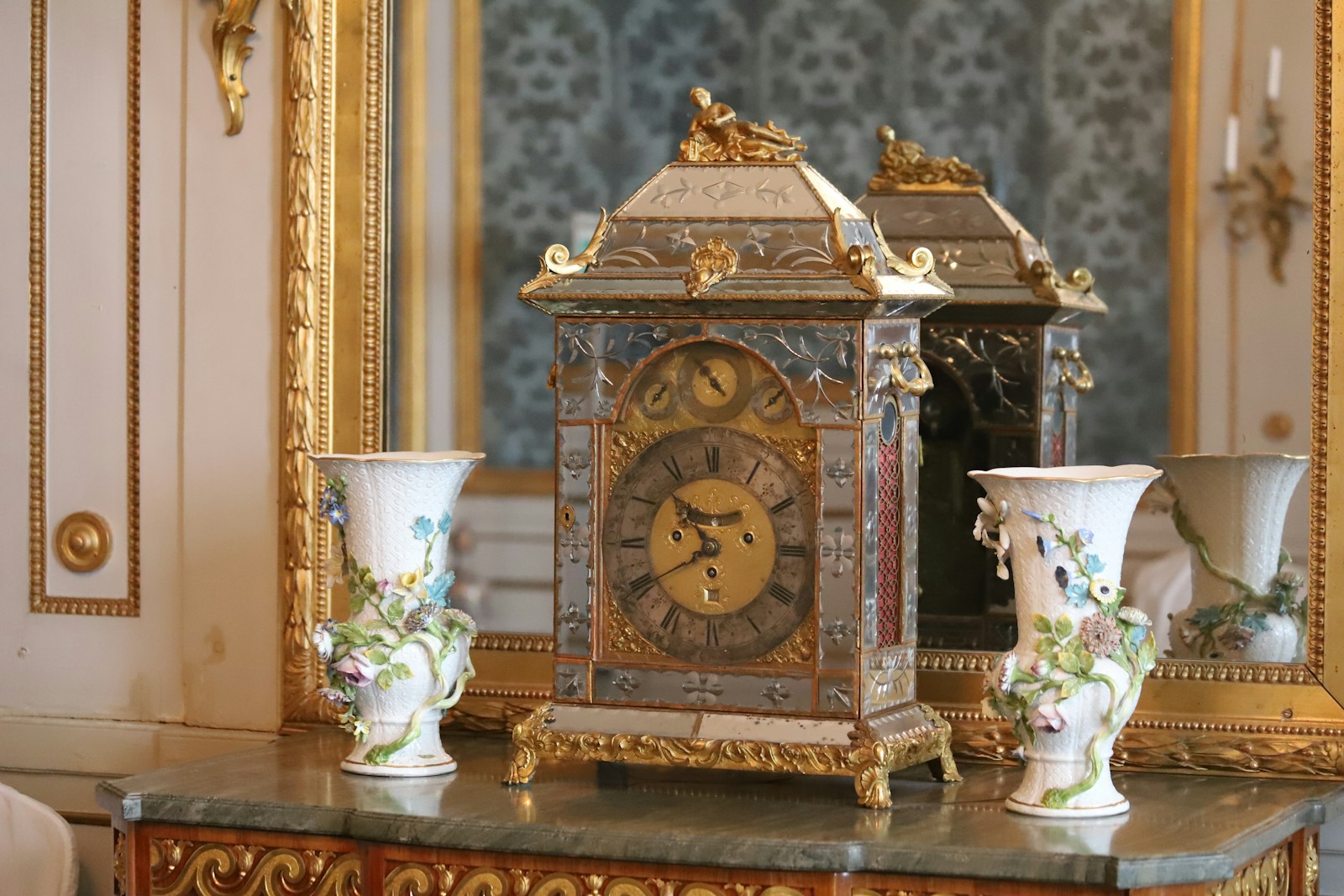 A clock sitting on top of a table next to vases
