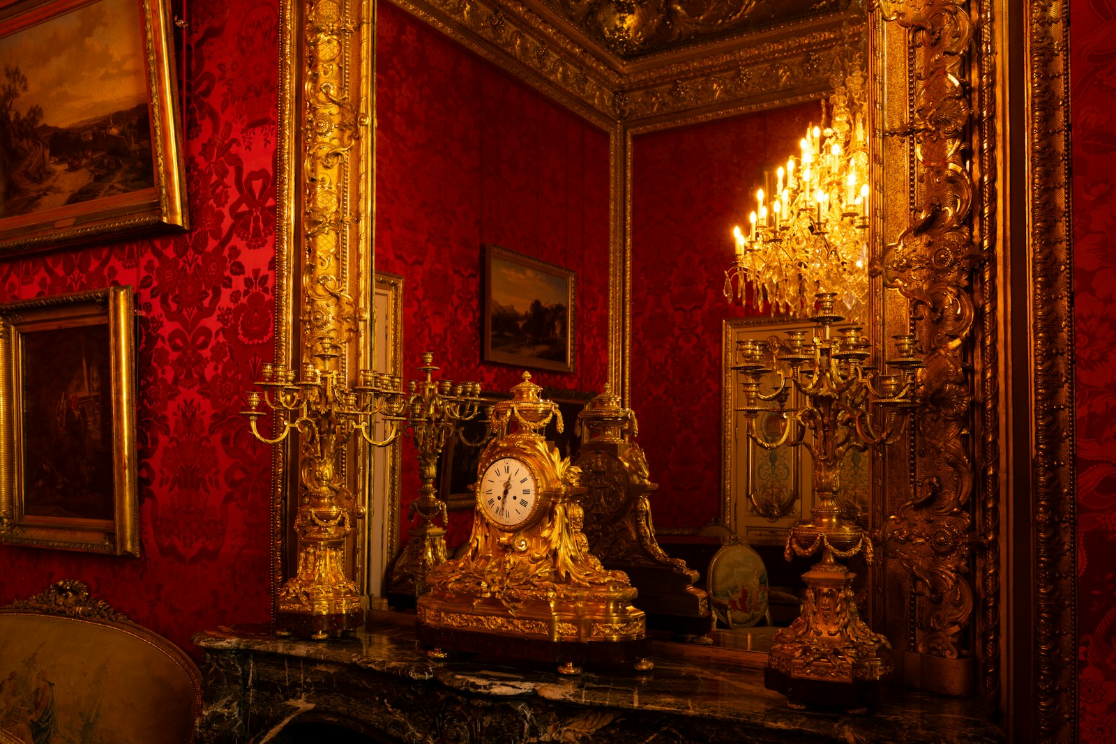 Ornate golden clock on a marble fireplace mantel.